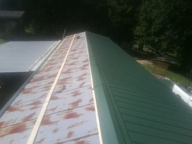 Old rusted panels beside newly installed green metal roofing — Wind Damage Roof Repair by Roofing Brothers in Owensville