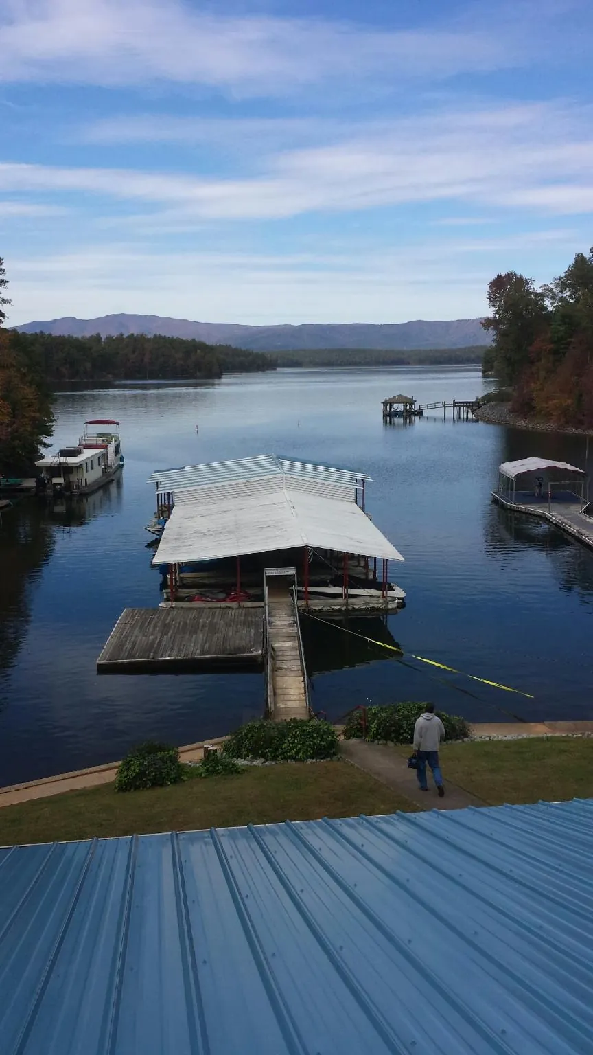 View across a lake from a newly installed blue metal roof in Owensville